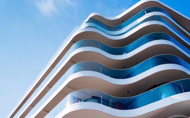 Modern commercial building with curved balconies against a blue sky
